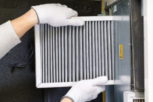 Universal Home Experts technician replacing air filter as part of HVAC maintenance.